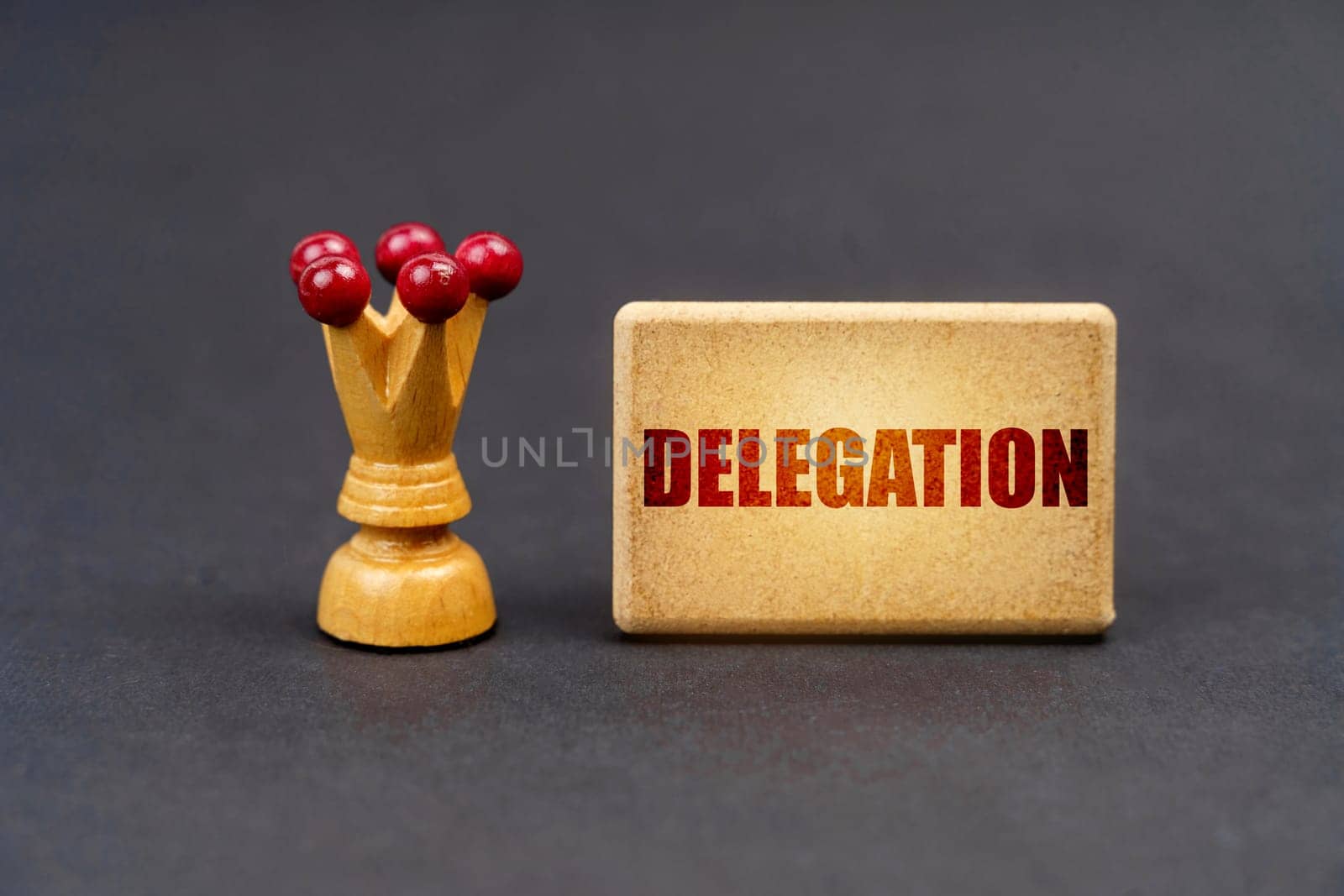 Leader concept. On a black surface there is a chess piece and a wooden block with the inscription - Delegation