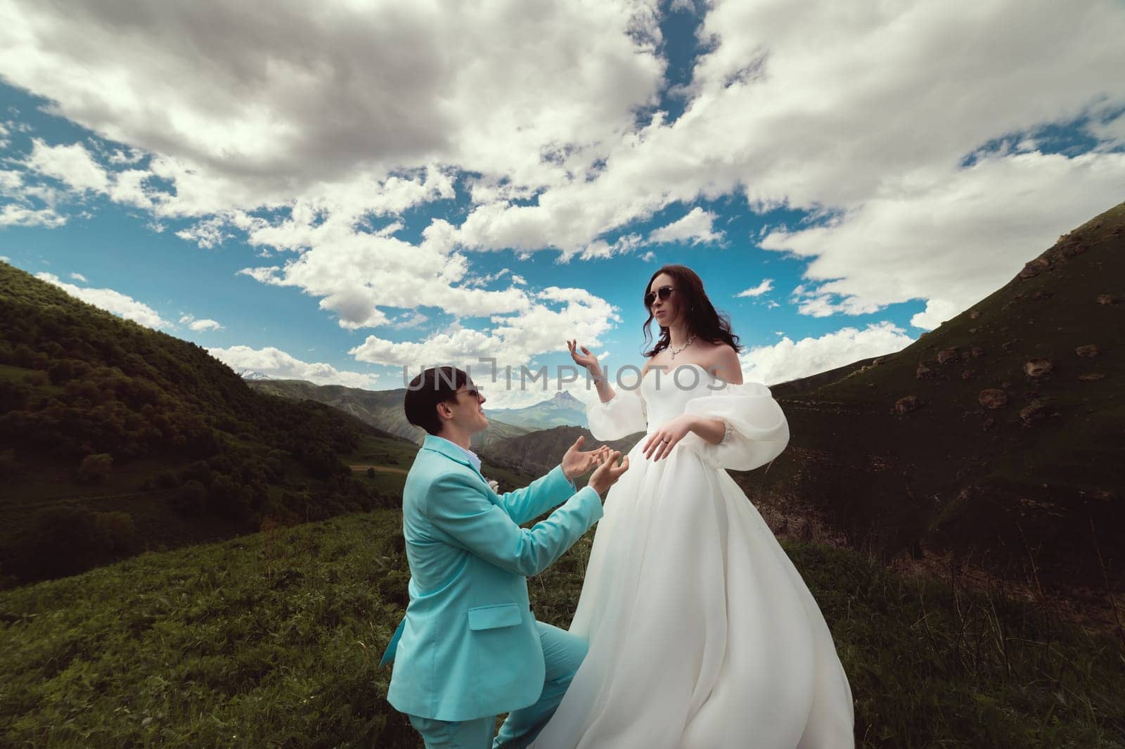 A man kneels on the grass and proposes to a woman. Emotional couple in love, engagement or wedding. The bride looks down at the groom.