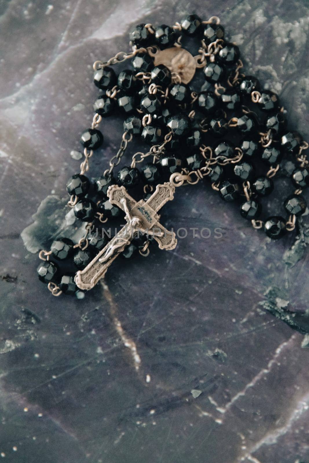 A close-up shot of a black beaded rosary and crucifix, symbolizing faith and spirituality. by jbruiz78