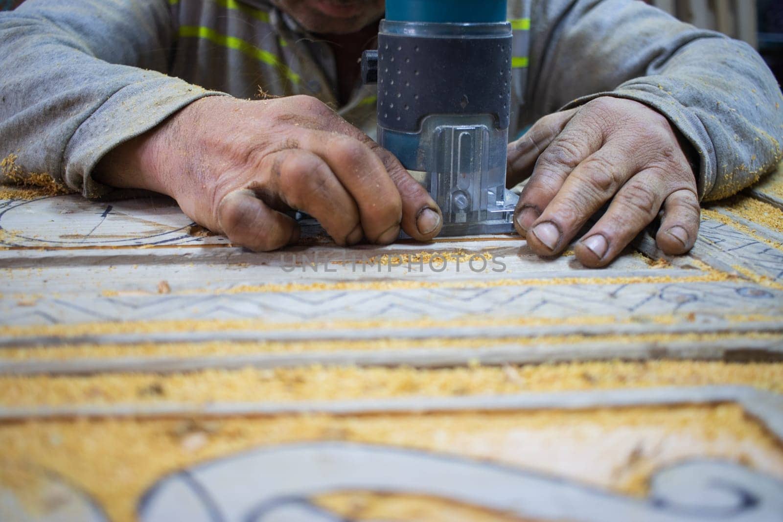 Close Up of Man Hands carving on wooden furniture. Carpenter using tool making Artistic Wood Carving. Producing an Ornament on Wood with Chisel and Hammer on a Panel of Wood by senkaya