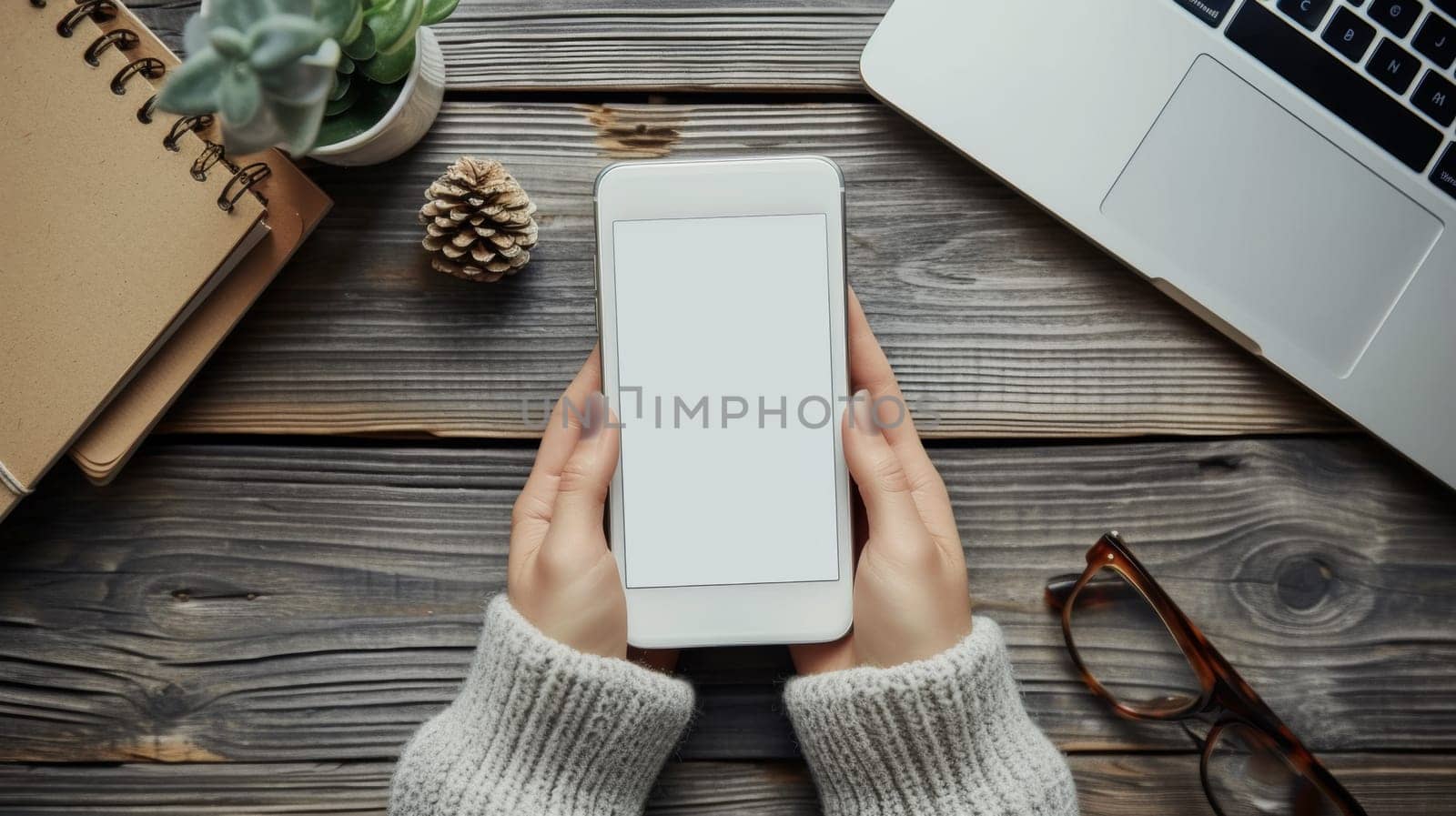 A person holding a cell phone with an empty screen on top of wooden table