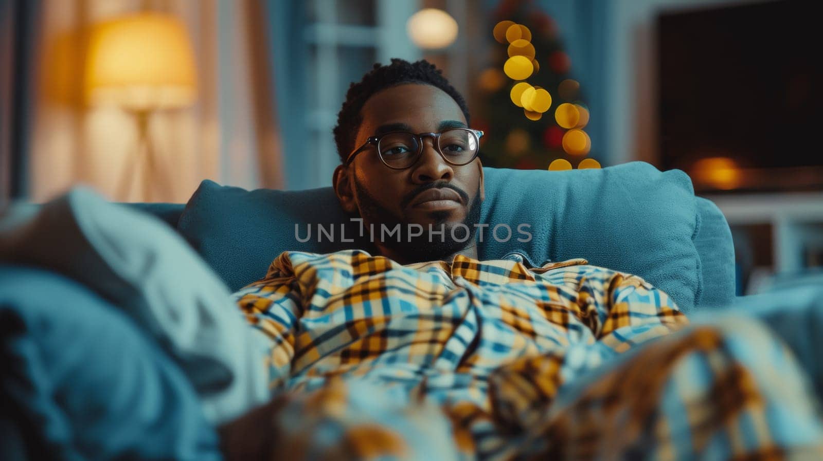 A man in pajamas sitting on a couch with his eyes closed
