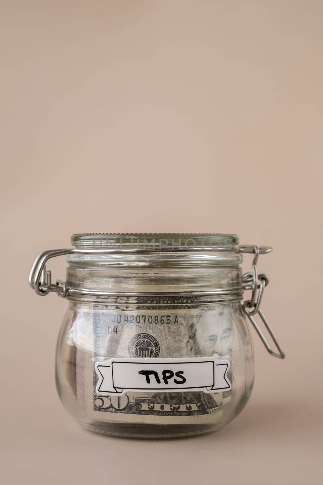 Glass jar full of American currency dollars cash banknote with text TIPS. Preparation saving money. Moderate consumption and economy. Collecting money