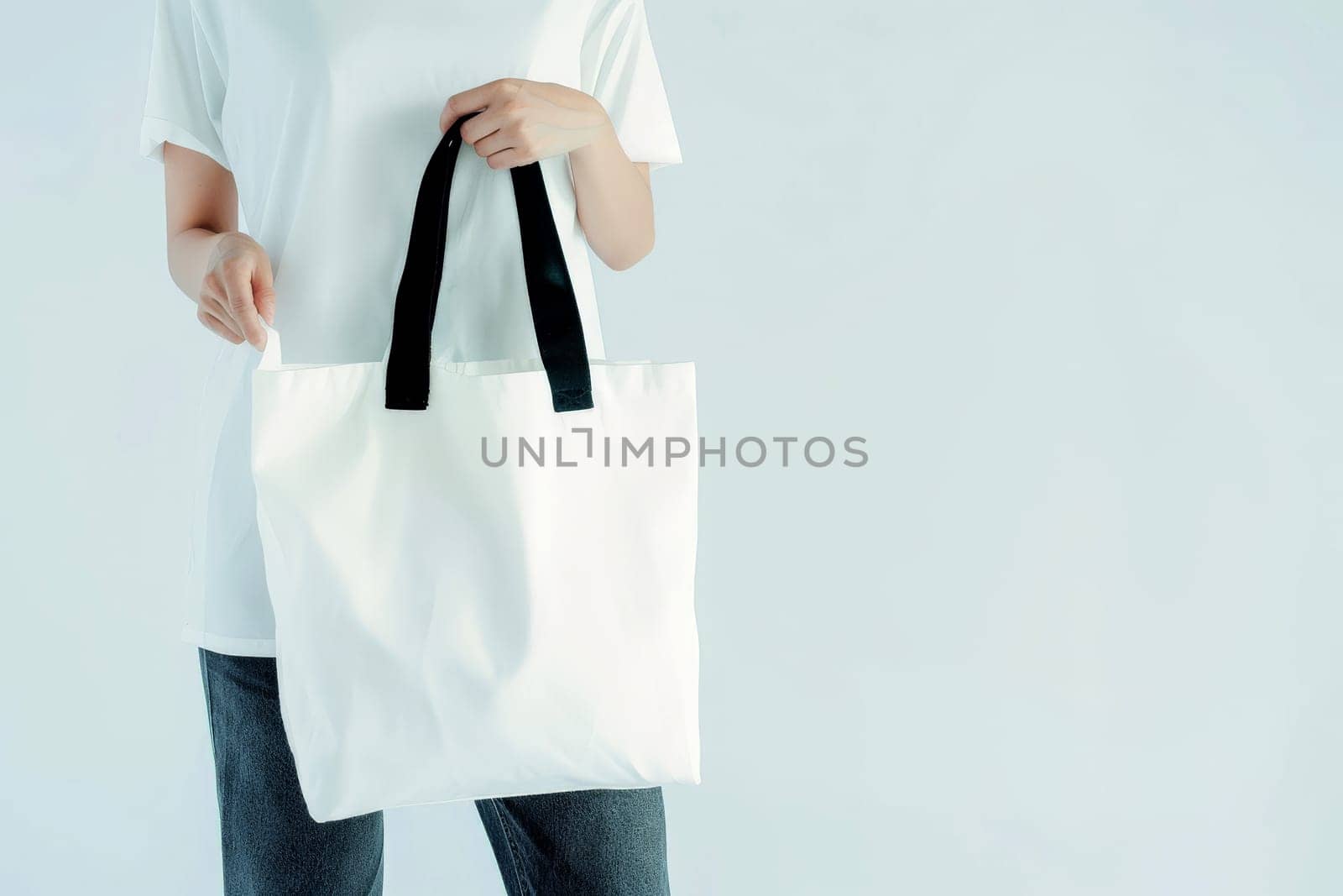 woman Hand holding a White Polyester square tote bag for mockup . AI generated image by matamnad