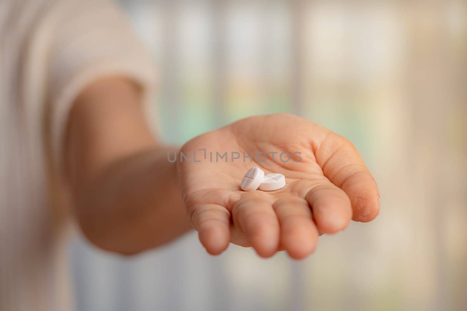 Woman hand holding pills on blurred background for medical and healthcare concept