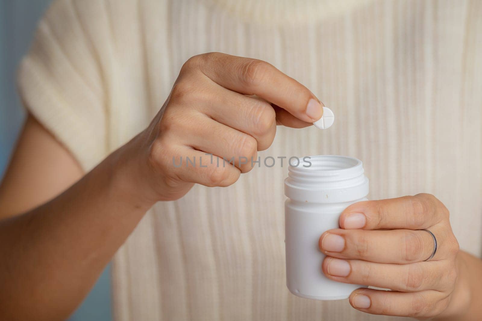 Closeup of woman hand holding white plastic bottle with pills for medical and healthcare concept, Focus on foreground.