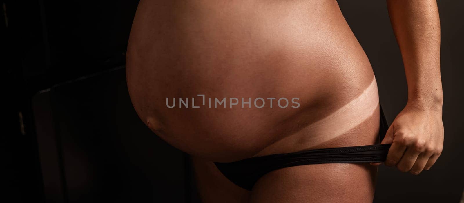 Pregnant woman pulls back her panties showing instant tan