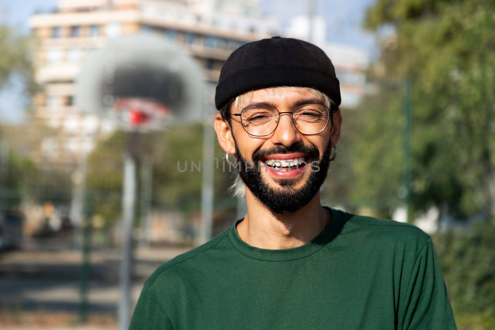 Headshot portrait of happy young caucasian man in basketball court outdoors looking at camera smiling. Copy space. Healthy lifestyle and sports concept.
