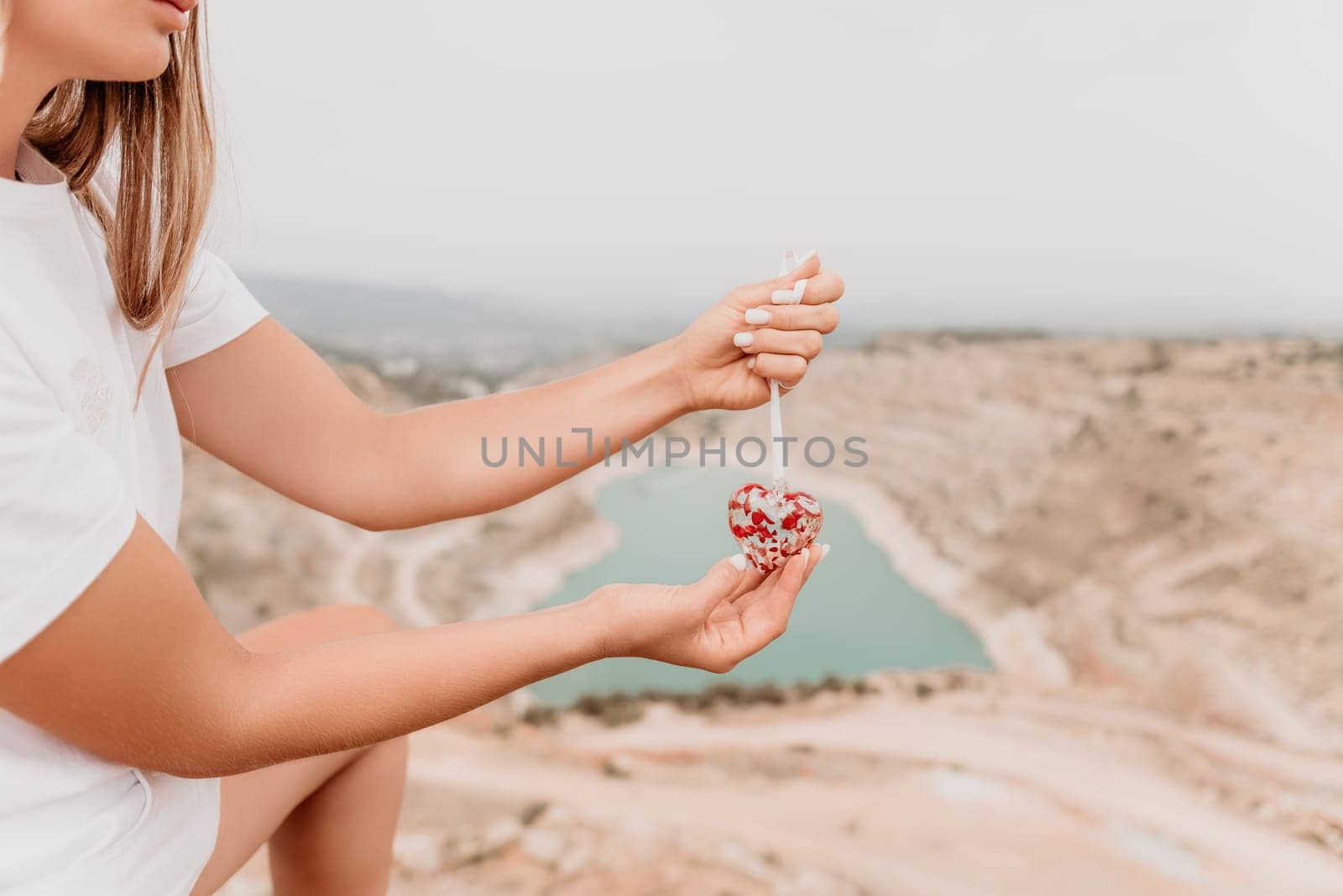 Woman travel portrait. Happy woman with long hair looking at camera and smiling. Close up portrait cute woman is posing on a heart shaped lake - travel destination by panophotograph