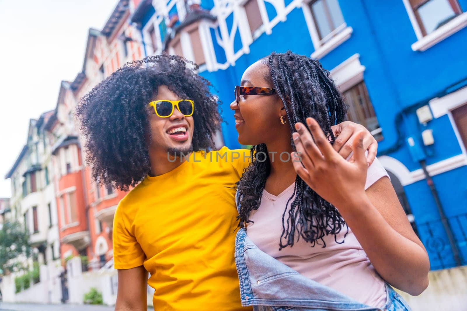 African modern couple talking and strolling along a colorful street by Huizi