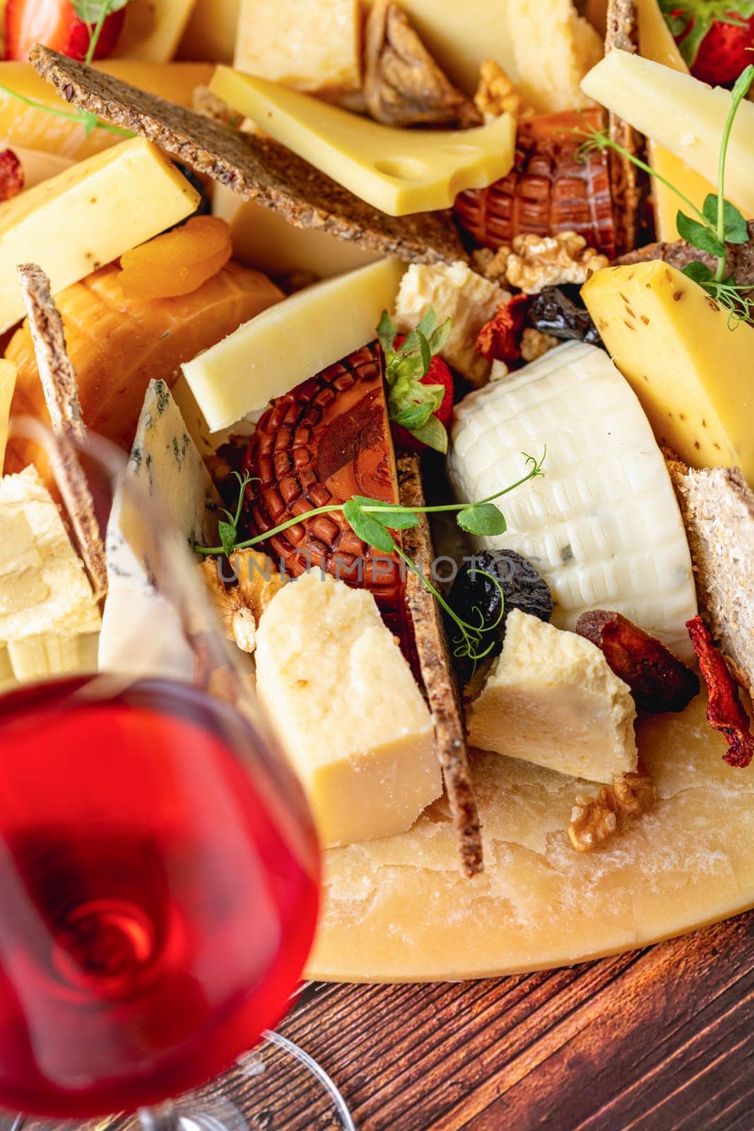 Cheese plate prepared with luxury cheeses and wine on wooden table by Sonat
