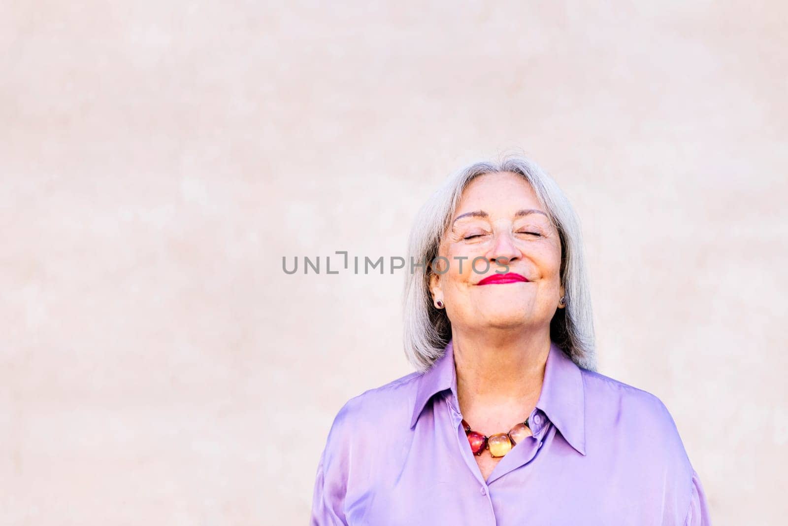 portrait of a nice senior woman smiling with eyes closed, elderly people happiness and active lifestyle concept, copy space for text