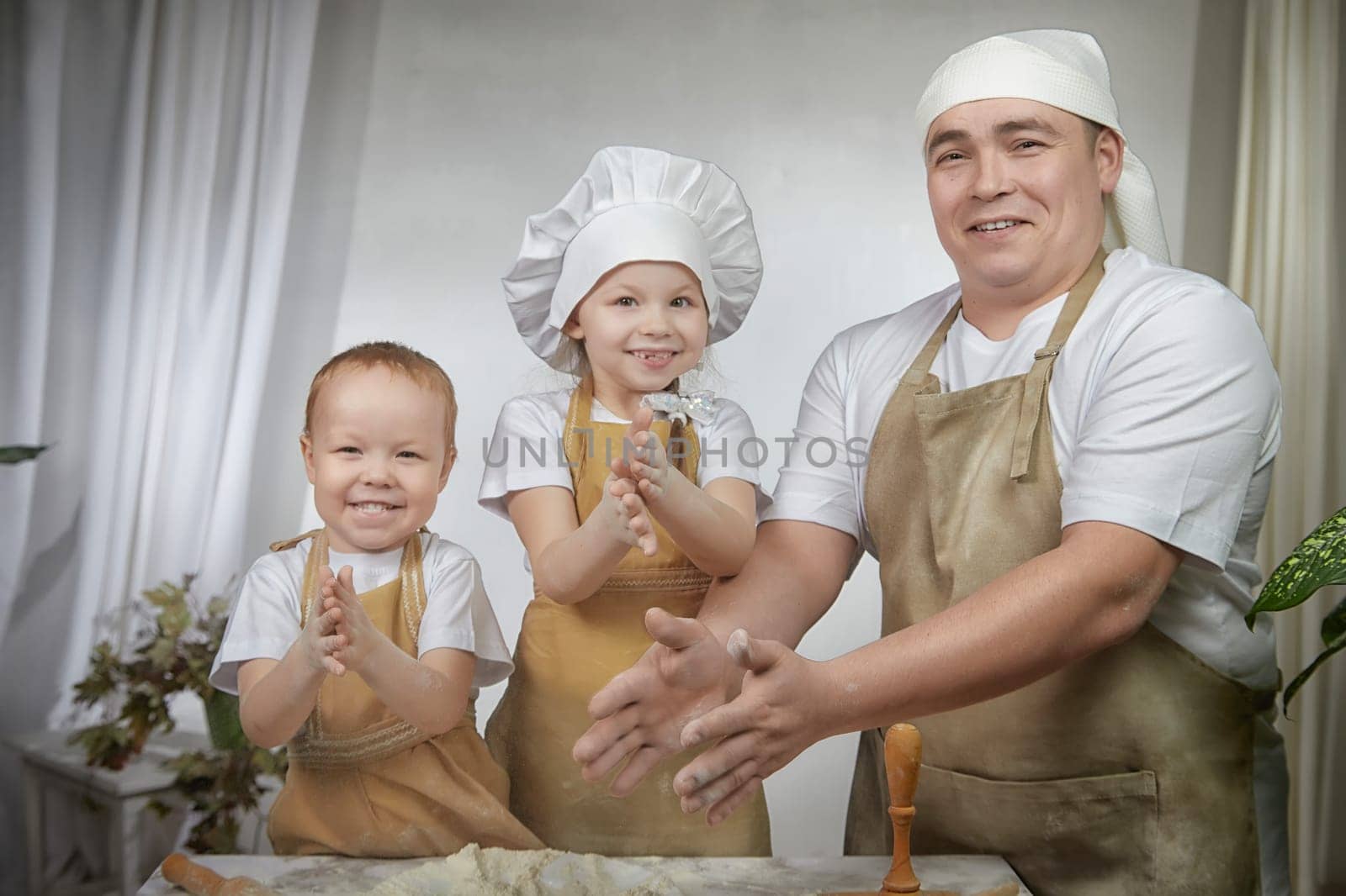 Cute oriental family with father, daughter, son cooking in kitchen on Ramadan, Kurban-Bairam, Eid al-Adha. Funny family at a cook photo shoot. Pancakes, pastries, Maslenitsa, Easter