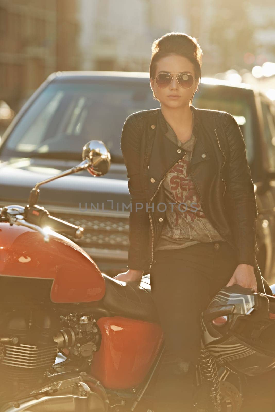 Bike, leather and woman in city with sunglasses for travel, transport or road trip as rebel. Fashion, street and model with attitude on classic or vintage motorcycle for transportation or journey by YuriArcurs
