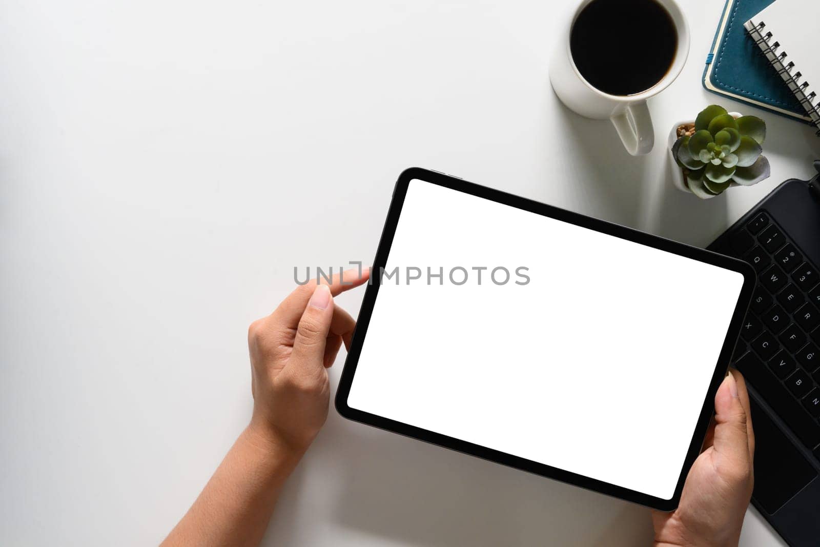 Above shot of woman hands holding digital tablet over white office desk. Empty display for advertising by prathanchorruangsak