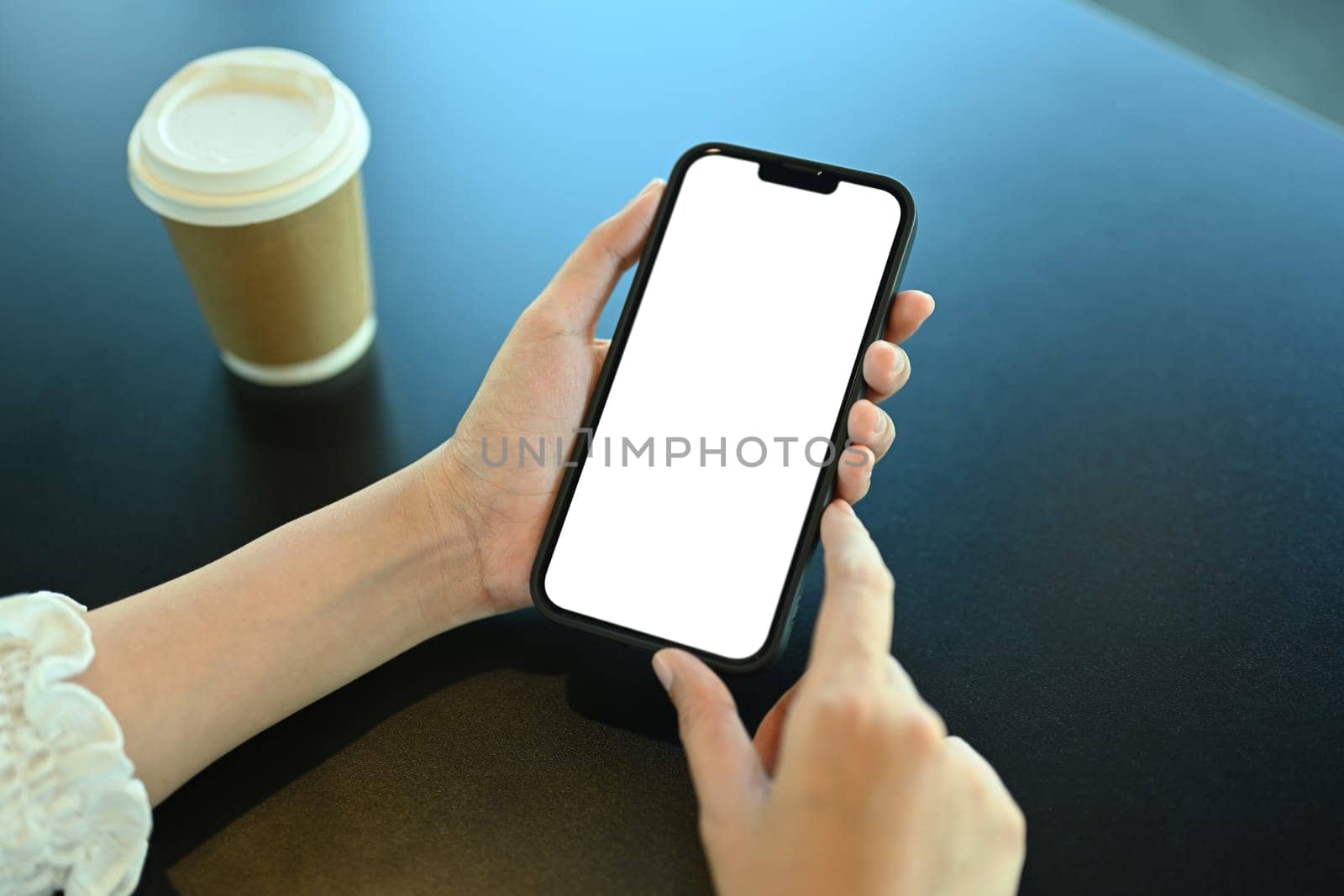 Closeup woman using smartphone on black table, blank screen for your advertising text by prathanchorruangsak