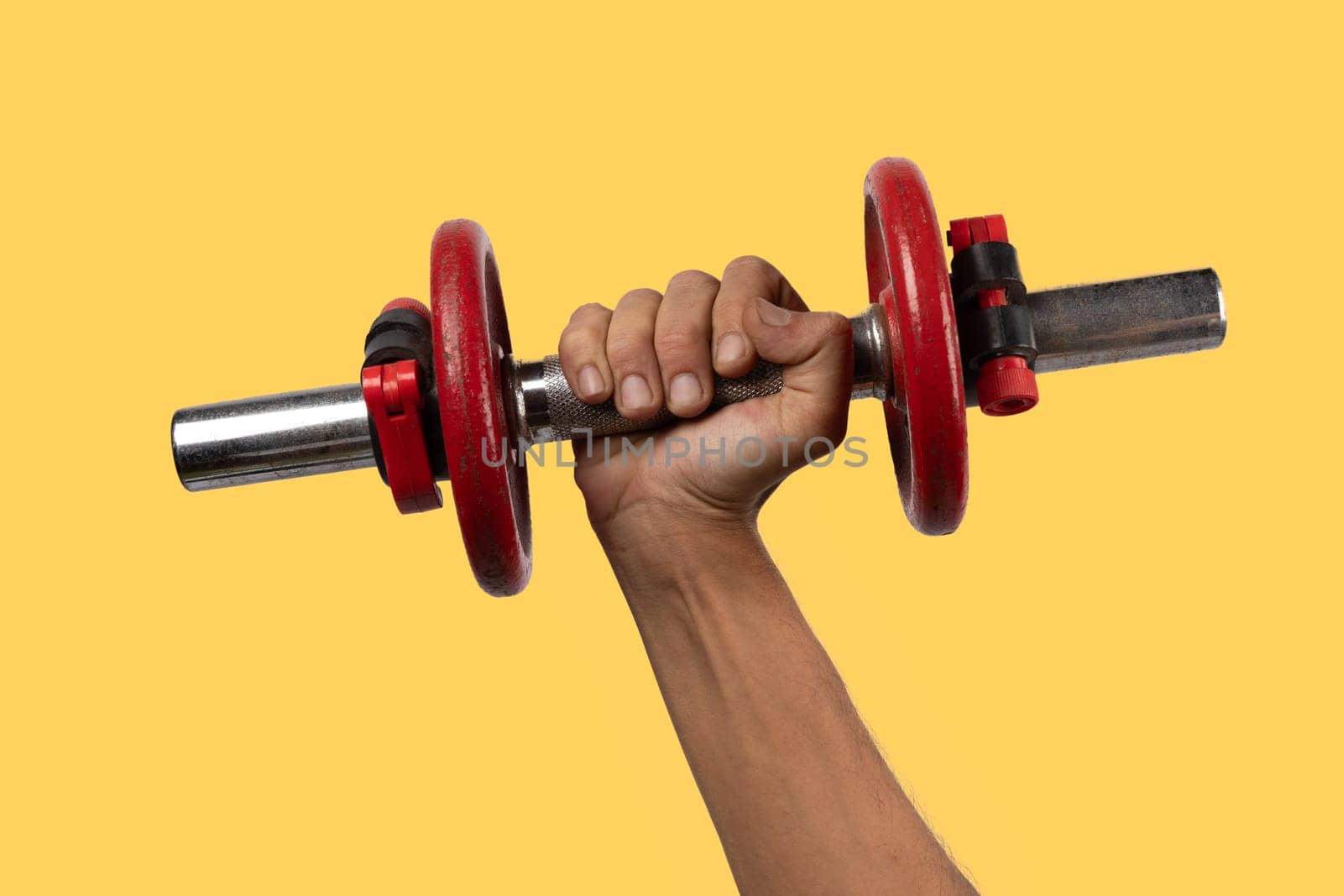 Black male hand holding an old red dumbell isolated on yellow background by TropicalNinjaStudio