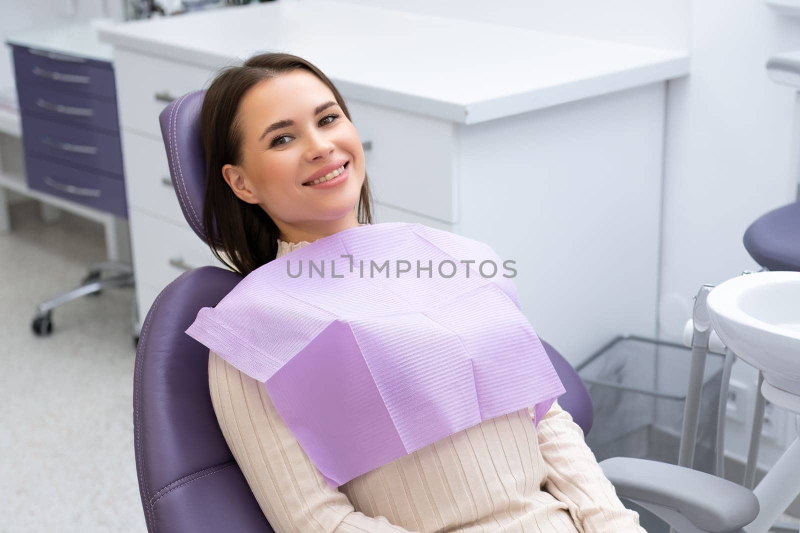 Young beautiful woman sitting in a dental chair waiting for the doctor in dental clinic by vladimka