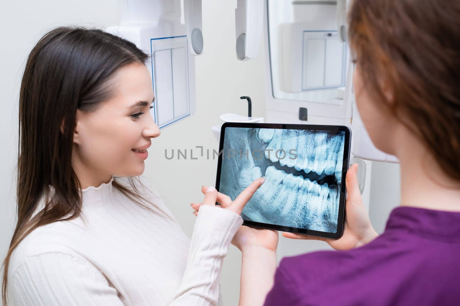 Dentist showing to patient jaw teeth x ray image at dental office by vladimka