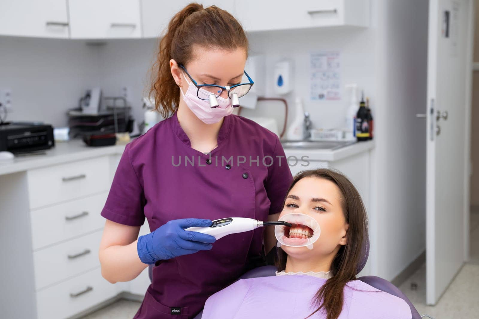 Dentist uses UV light completing dental filling procedure at appointment. UV light causes dental material to chemically bond with tooth enamel