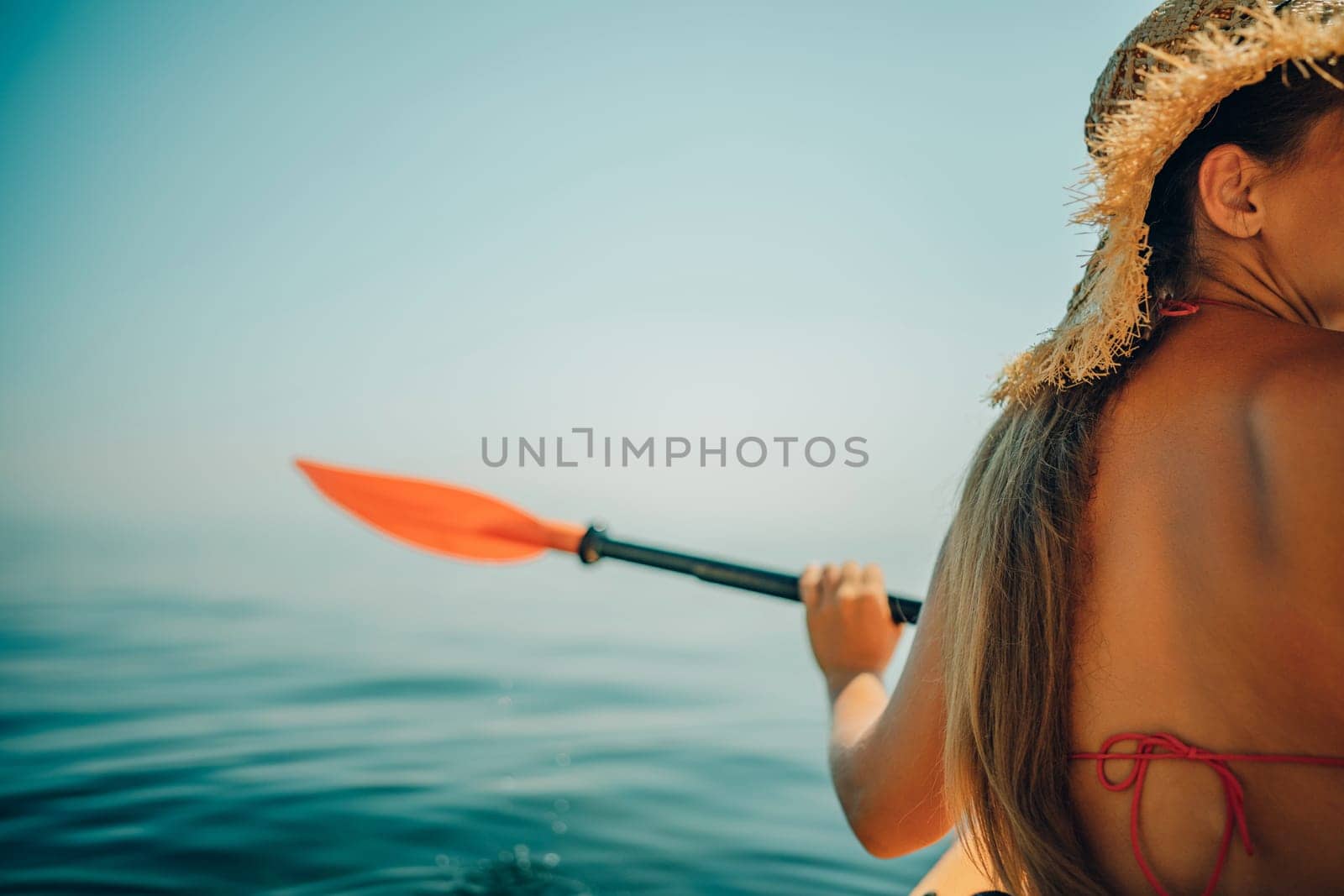 Woman in kayak back view. Happy woman with long hair in a swimsuit and hat floating in kayak on the sea. Summer holiday vacation. Summer holidays vacation at sea. by Matiunina