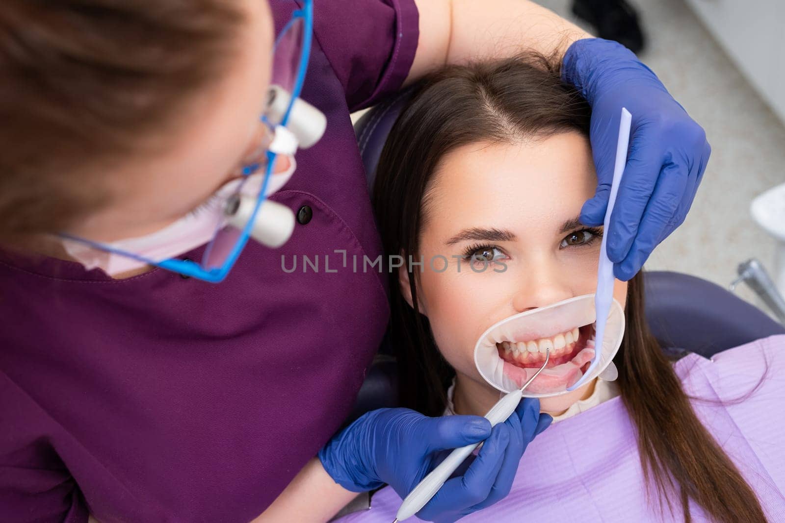 Dentist in gloves places temporary dental filling with instrument in clinic. Dental professional fills tooth space with filling composition