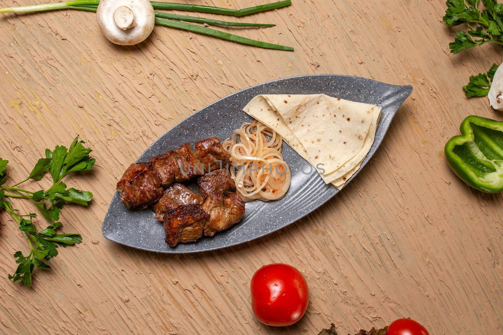 Grilled meat and vegetables on a rustic wooden table with soft flatbread. Succulent meat, tender veggies, vibrant tomatoes, peppers, mushrooms, onions create a delicious meal.