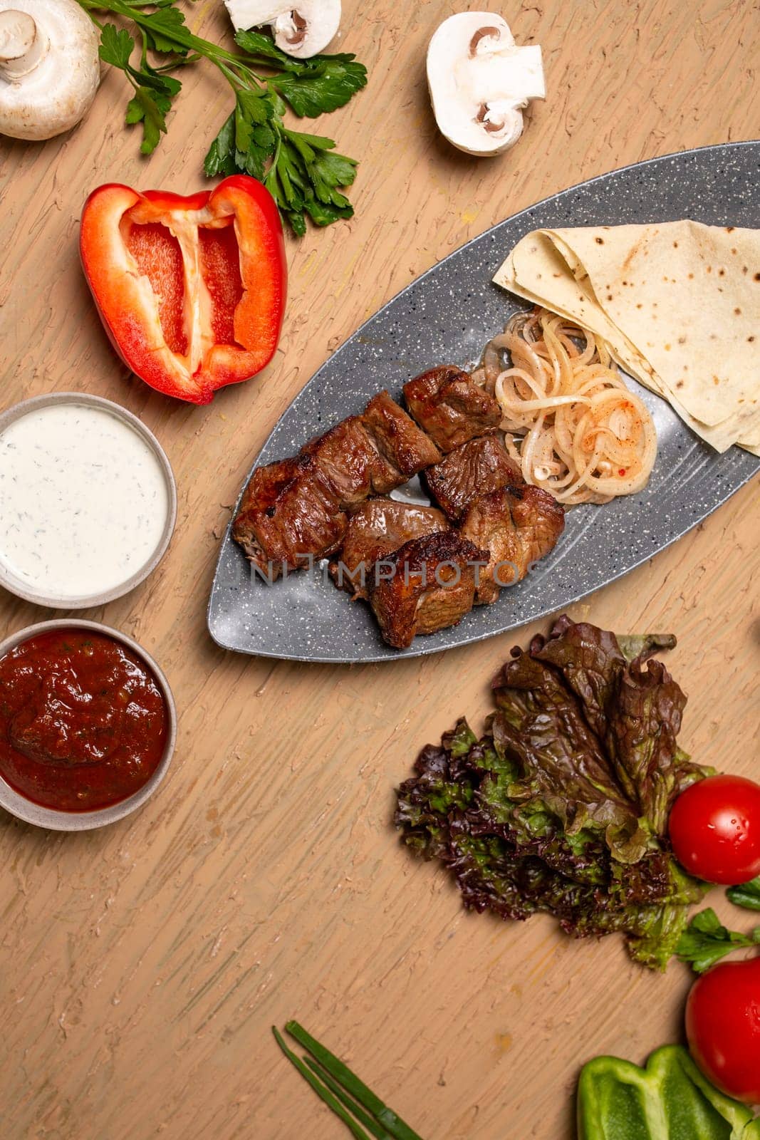 Juicy meat kebab with vegetables and herbs on a wooden table. view from above.