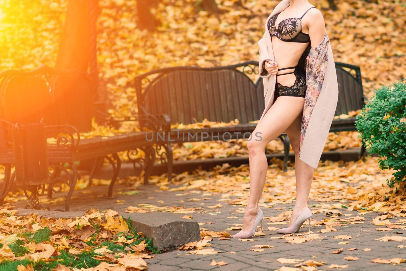 Fashion portrait of sexy woman in face mask and lingerie in autumn park. Pandemic, virus, coronavirus