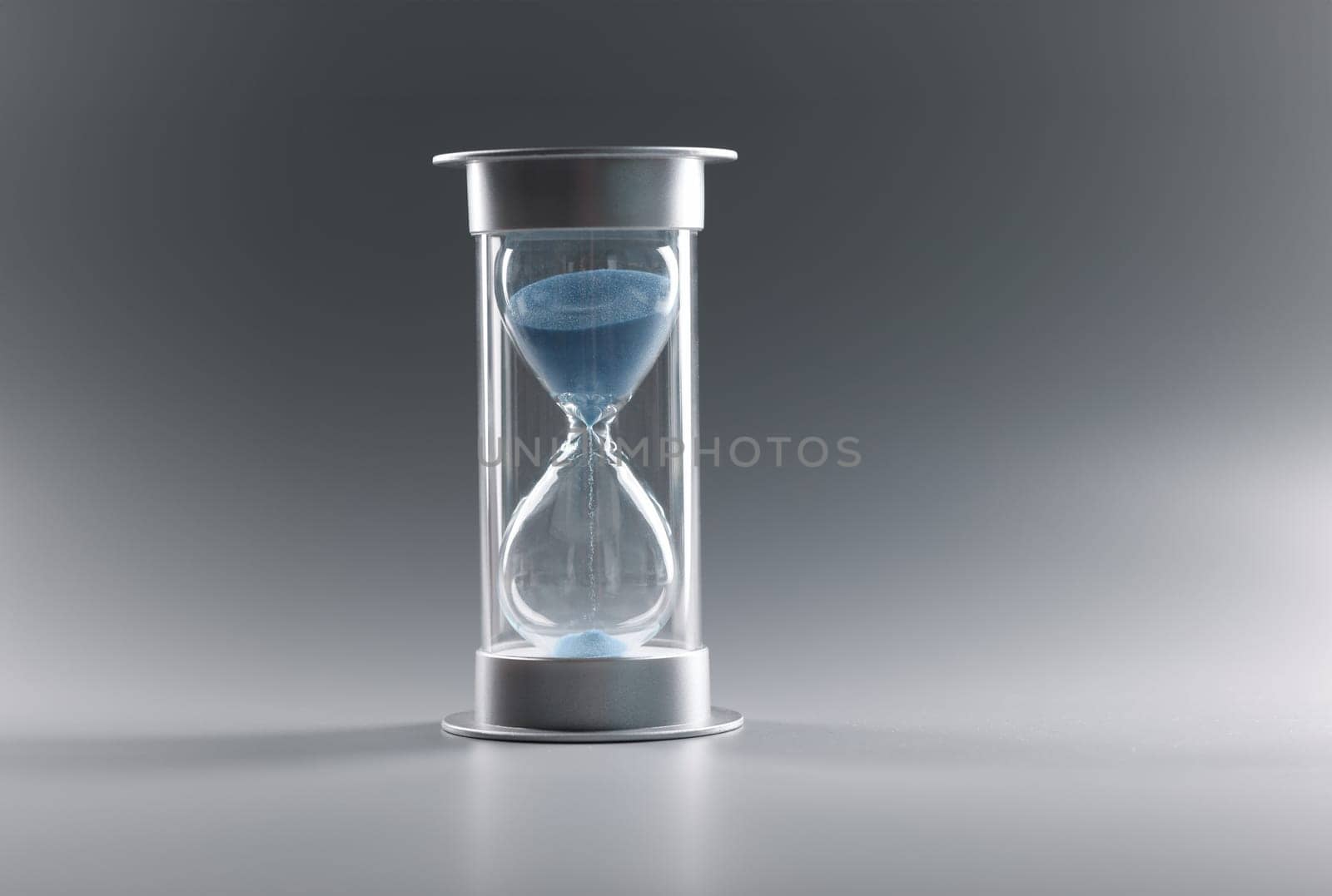 Closeup of hourglass with blue sand on gray background. Time management concept