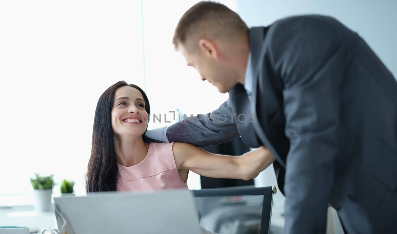 Young man and woman in business suits hugging at work in office. Love affairs at work concept