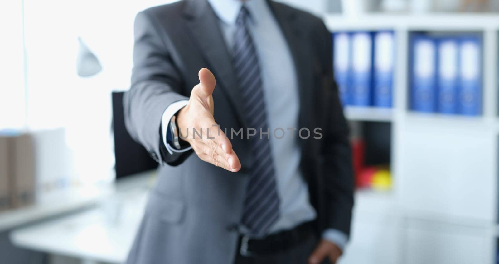Man in business suit stretching out his hand for handshake closeup by kuprevich