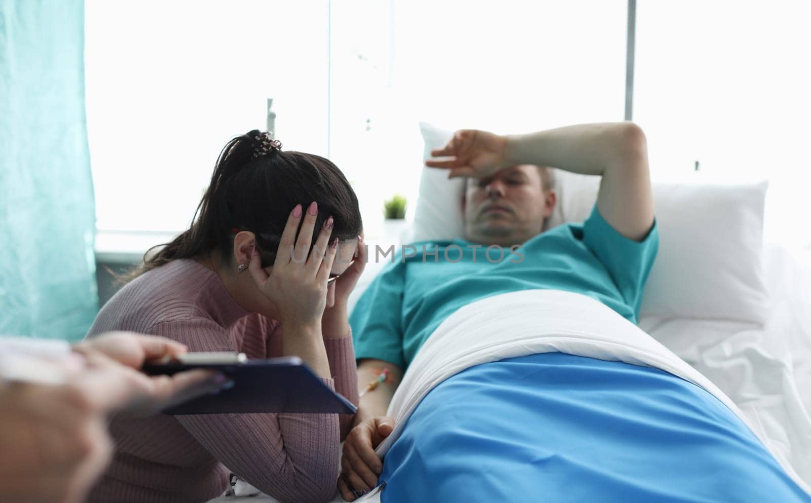 Upset woman sitting near man in hospital bed by kuprevich