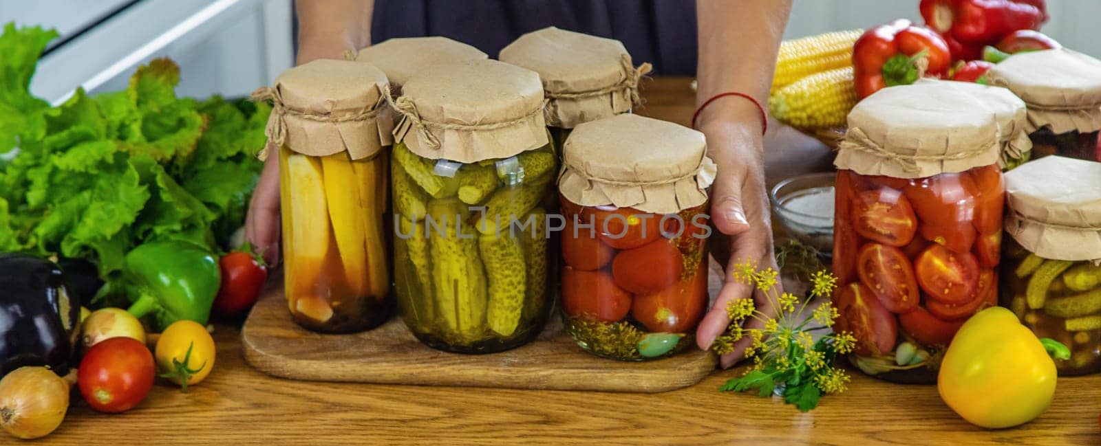 Woman canning vegetables in jars in the kitchen. Selective focus. Food.