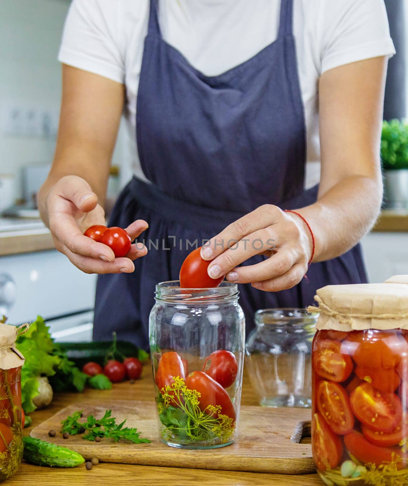 Woman canning vegetables in jars in the kitchen. Selective focus. Food.