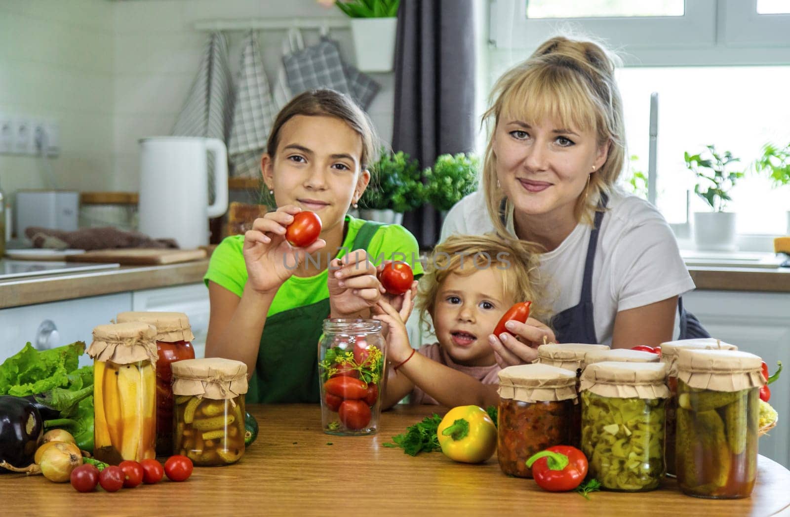 Family canning vegetables in jars in the kitchen. Selective focus. Food.