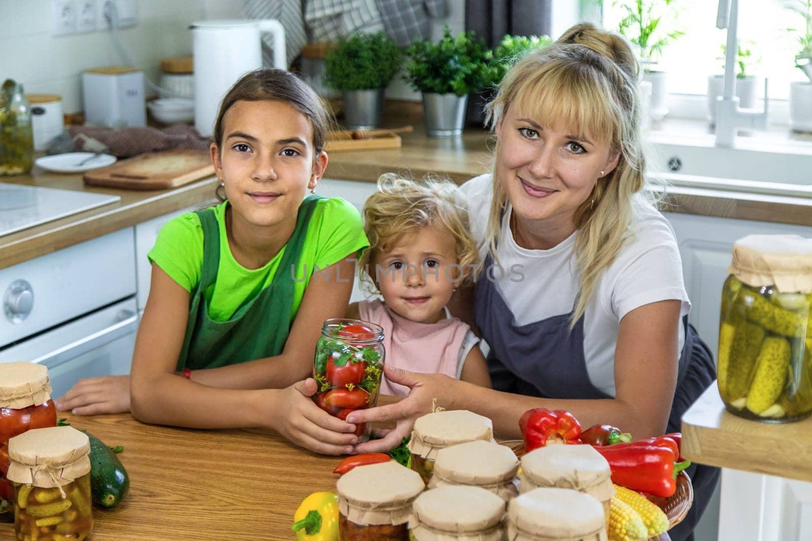 Family canning vegetables in jars in the kitchen. Selective focus. by yanadjana