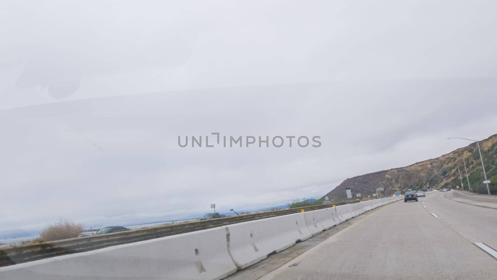 Driving along Highway 101 near Rincon Beach, California, amidst a gloomy, cloudy winter day.