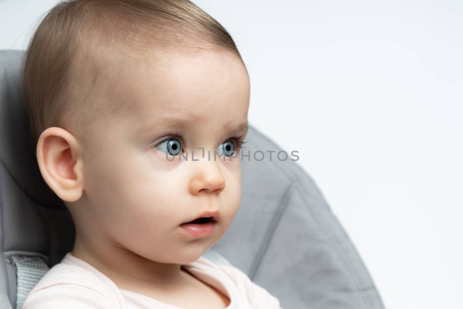 Baby in a highchair, with a thoughtful and innocent gaze. Ideal for illustrating articles on early childhood development, this image conveys the depth of a young child's contemplation and the purity of early life experiences.
