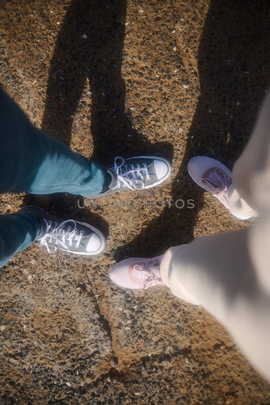 Top view of male and female feet in sports shoes or sneakers, standing on the rocky cliff. POV by artgf