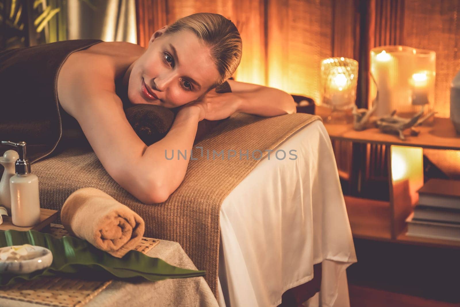 Caucasian woman customer enjoying relaxing anti-stress spa massage and pampering with beauty skin recreation leisure in warm candle lighting ambient salon spa at luxury resort or hotel. Quiescent