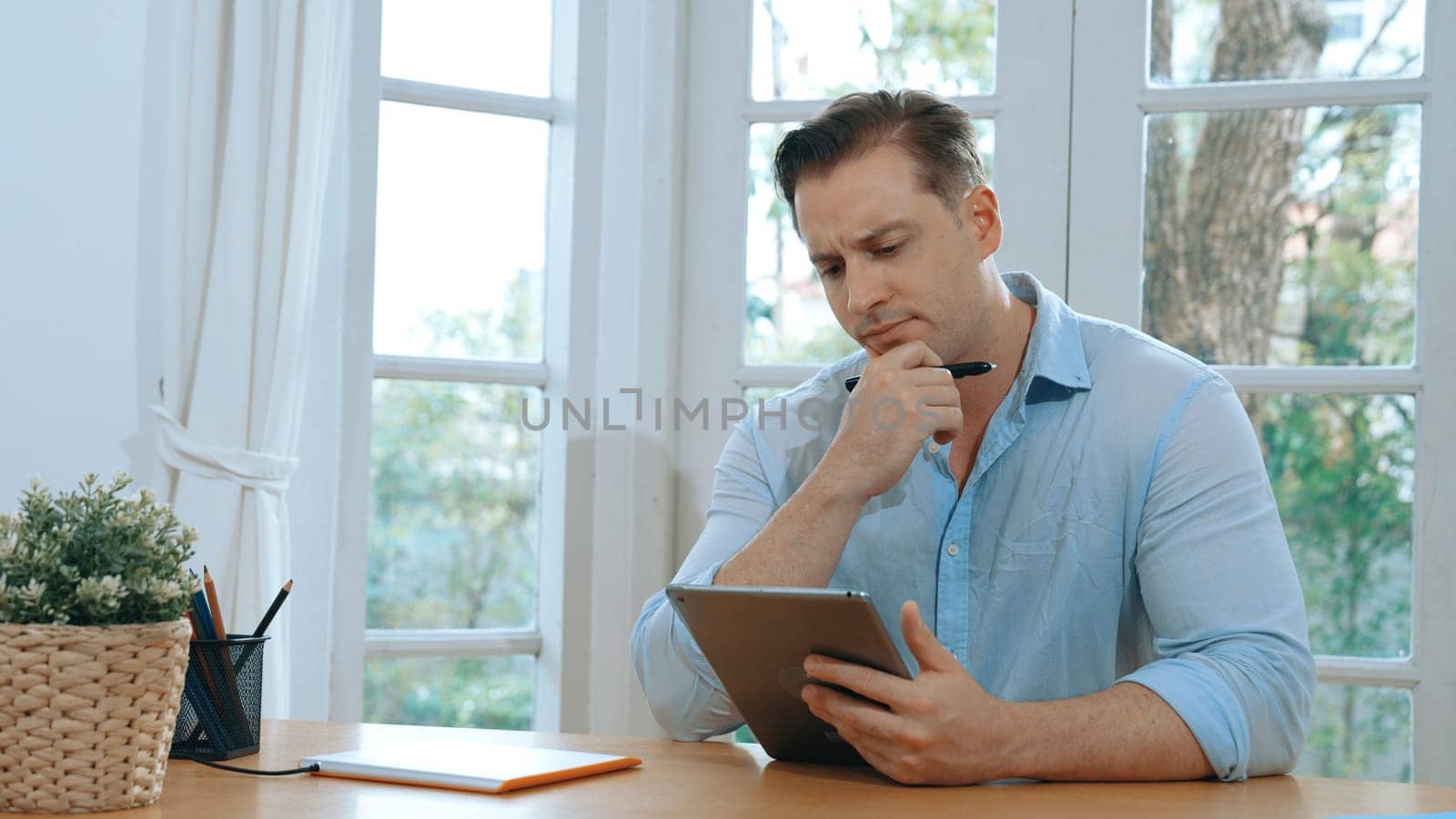 Businessman struggle to solve work problem from home using laptop, sitting on his desk at home office with stressed and frustrated expression, trying to figure out solution for problem. Synchronos
