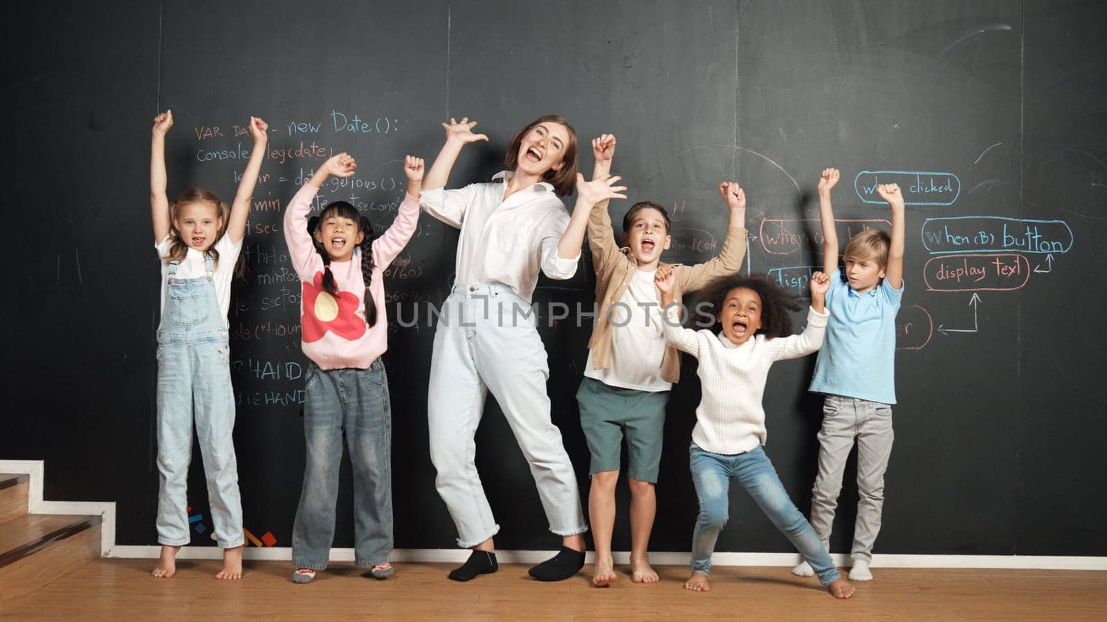 Multicultural happy student and teacher smiling and standing at blackboard with engineering code or prompt written. Kid express feeling of happy and enjoy with studying in STEM classroom. Erudition.