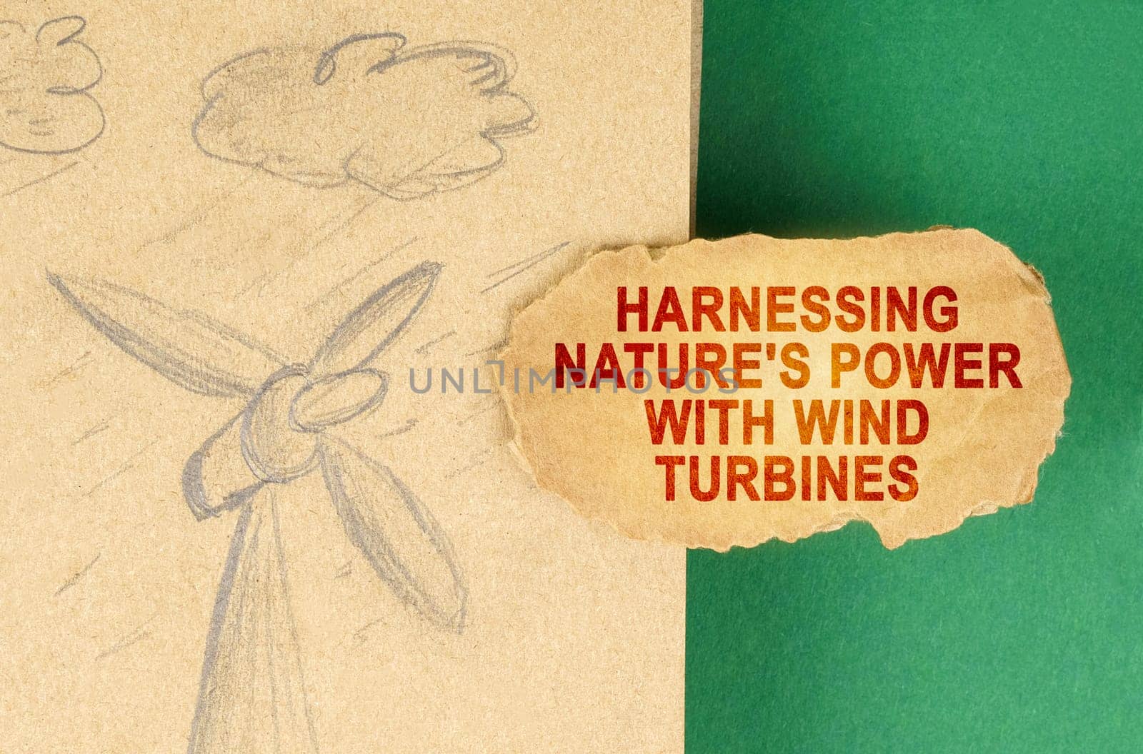 Alternative energy concept. On a green surface there is a drawing with a wind generator and a cardboard with the inscription - Harnessing nature's power with wind turbines