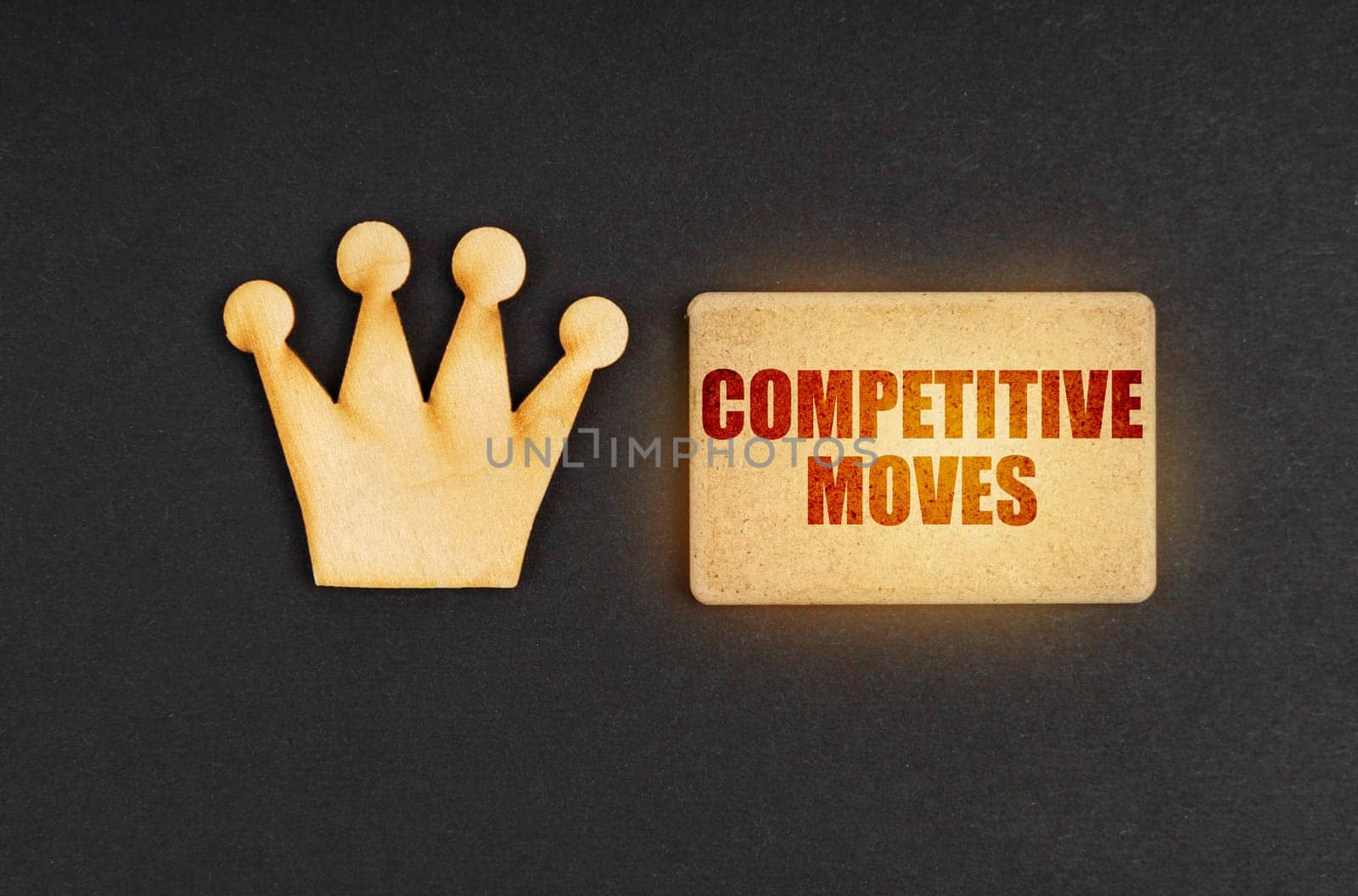 Business concept. On a black background there is a wooden crown of the leader and a sign with the inscription - Competitive Moves