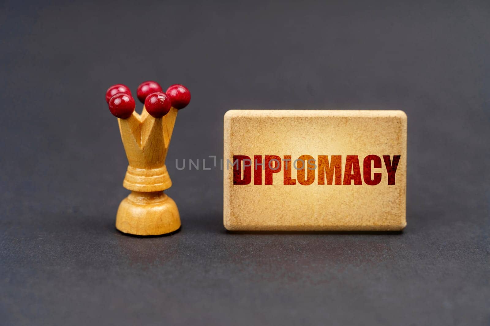 Leader concept. On a black surface there is a chess piece and a wooden block with the inscription - Diplomacy