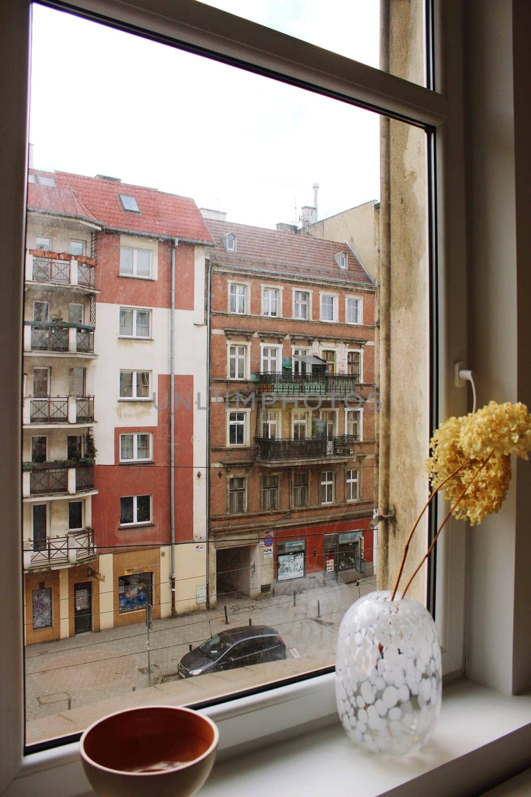 View from the window to the street with a colorful old house. High quality photo