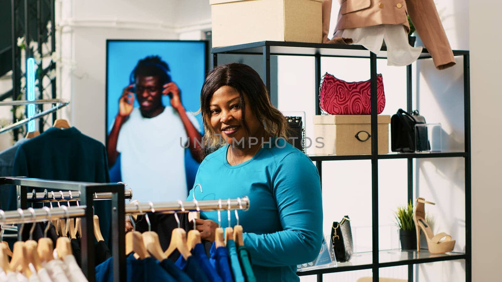 African american customer looking at with trendy shirt, checking items material in clothing store. Shopaholic woman analyzing new fashion collection, shopping for casual wear in modern boutique