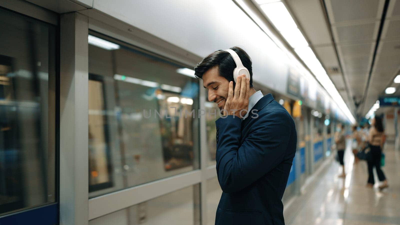 Manager wearing headphone at train station while holding mobile phone. Exultant. by biancoblue