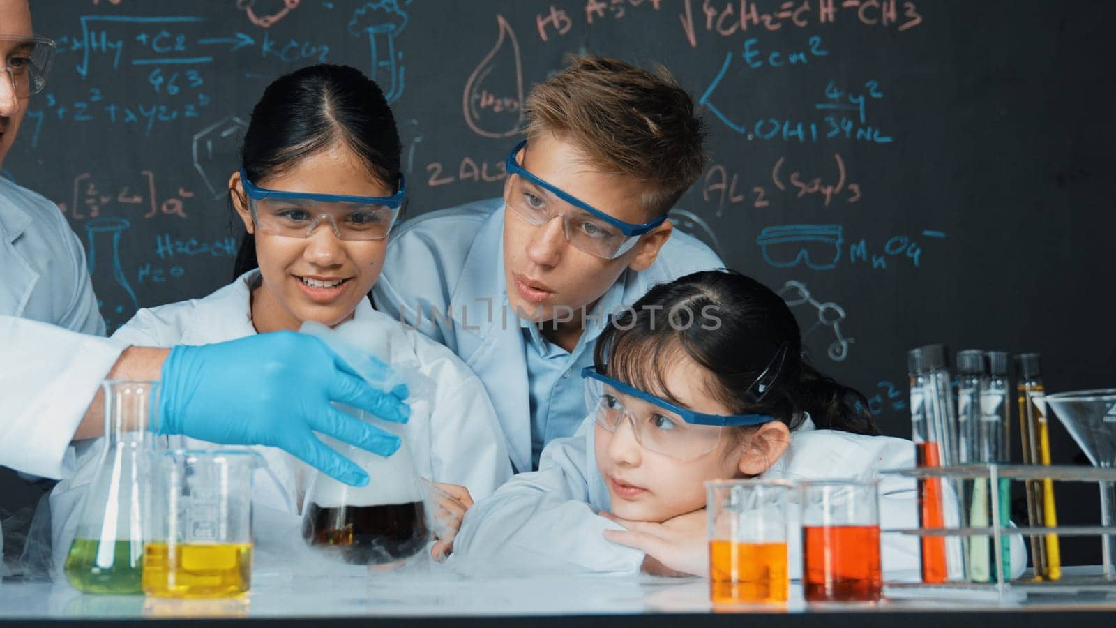 Cute girl looking at beaker while doing experiment in STEM class. Edification. by biancoblue